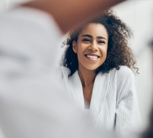 Woman practicing free self-care at home by looking her reflection on the mirror
