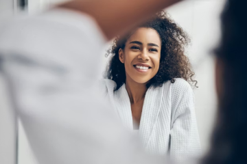Woman practicing free self-care at home by looking her reflection on the mirror