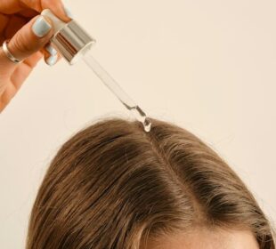 a lady applying a hair growth oil on her hair