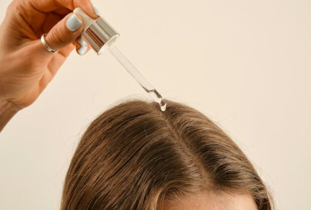 a lady applying a hair growth oil on her hair