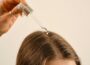 a lady applying a hair growth oil on her hair