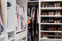 Organized closet with clothes arranged by color, folded shelves, storage baskets, and neatly lined shoes.
