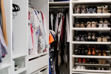 Organized closet with clothes arranged by color, folded shelves, storage baskets, and neatly lined shoes.