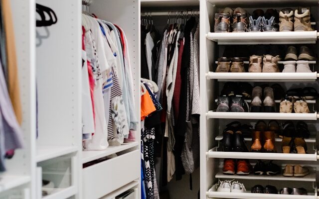 Organized closet with clothes arranged by color, folded shelves, storage baskets, and neatly lined shoes.