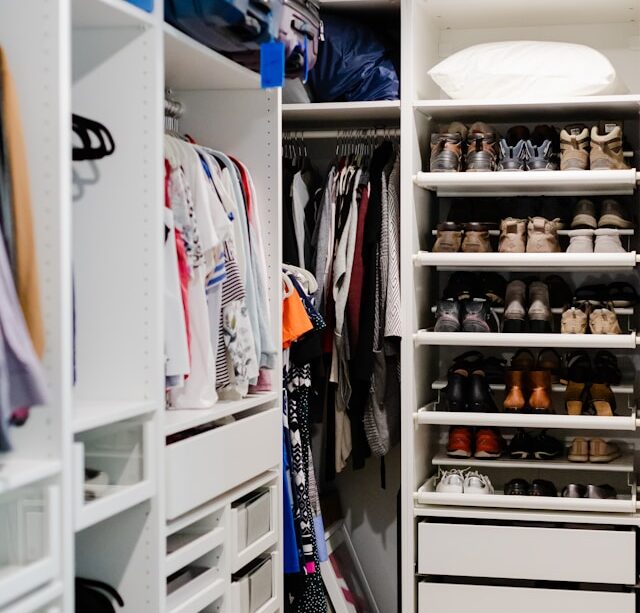 Organized closet with clothes arranged by color, folded shelves, storage baskets, and neatly lined shoes.