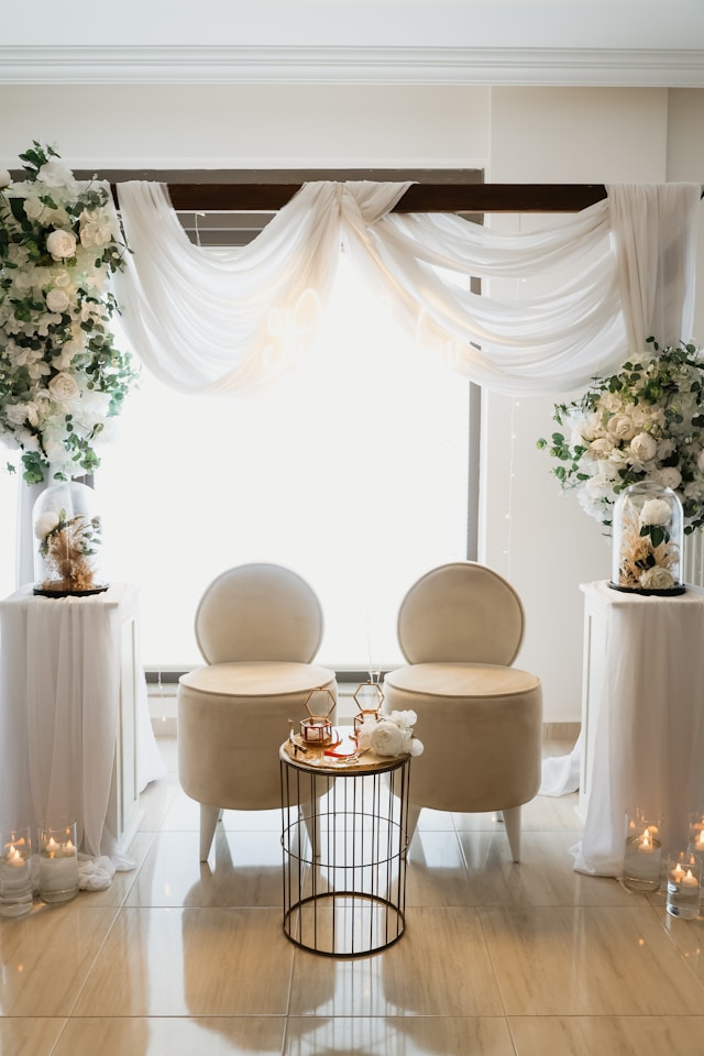 Wedding backdrop styled with ivory fabric draping and minimal flowers