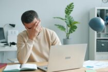 Person at desk showing emotional burnout symptoms with head in hands