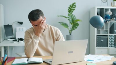 Person at desk showing emotional burnout symptoms with head in hands