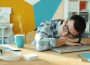 a man sleeping on a desk with coffee and laptop